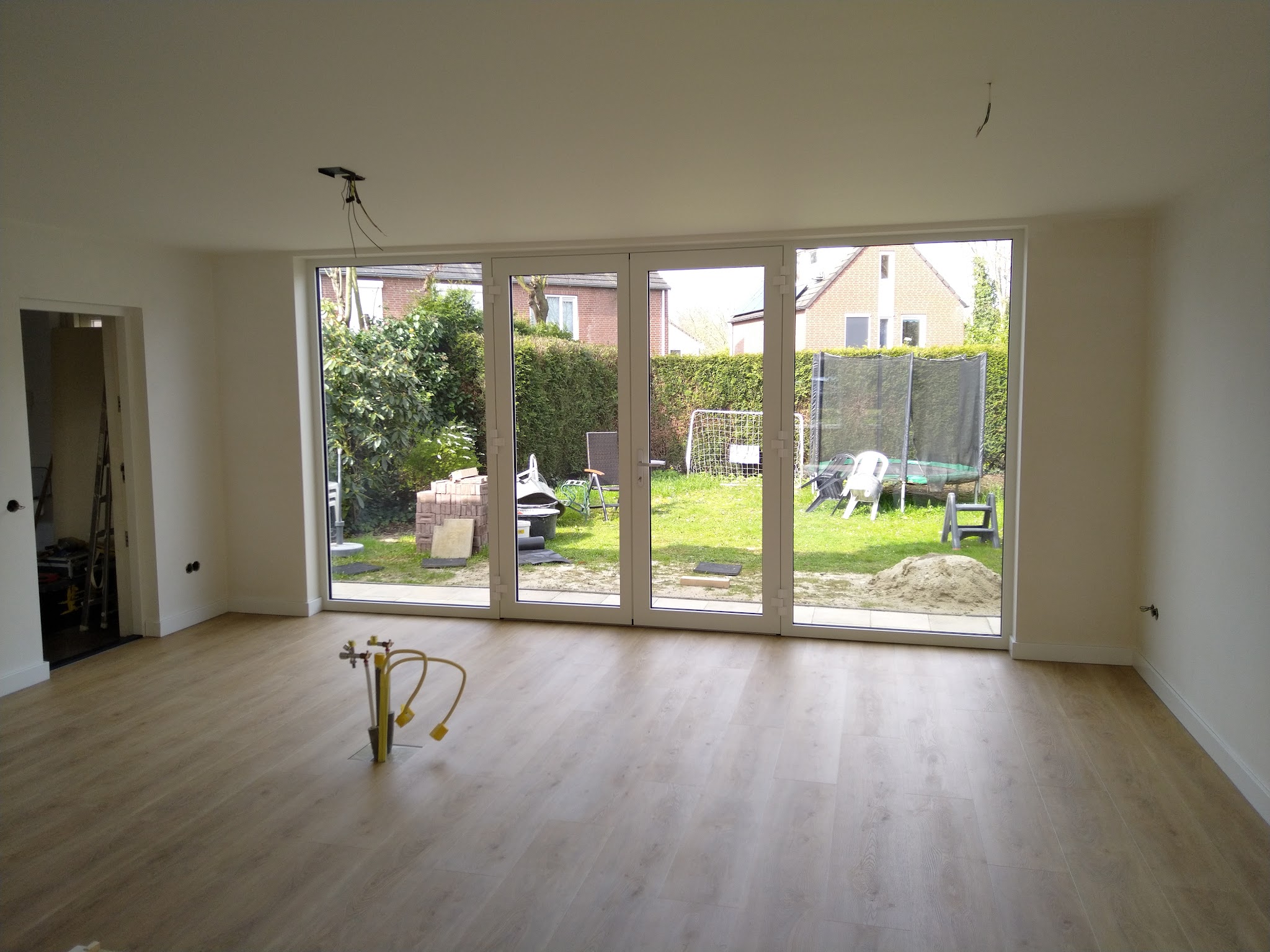Woonkamer na renovatie met nieuwe vloer en een glazen pui over de hele breedte
