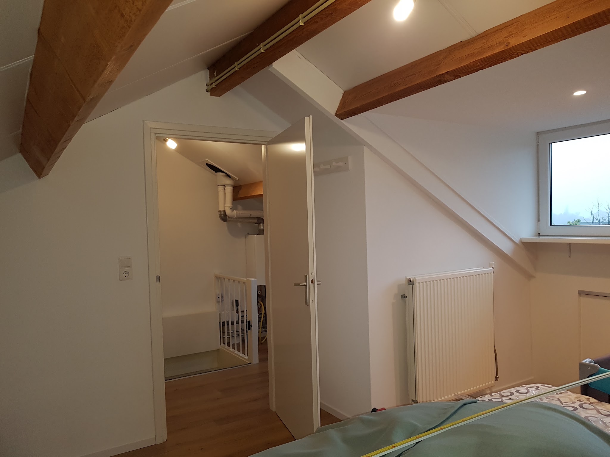 Zolderkamer met houten balken, nieuwe deuren en radiator