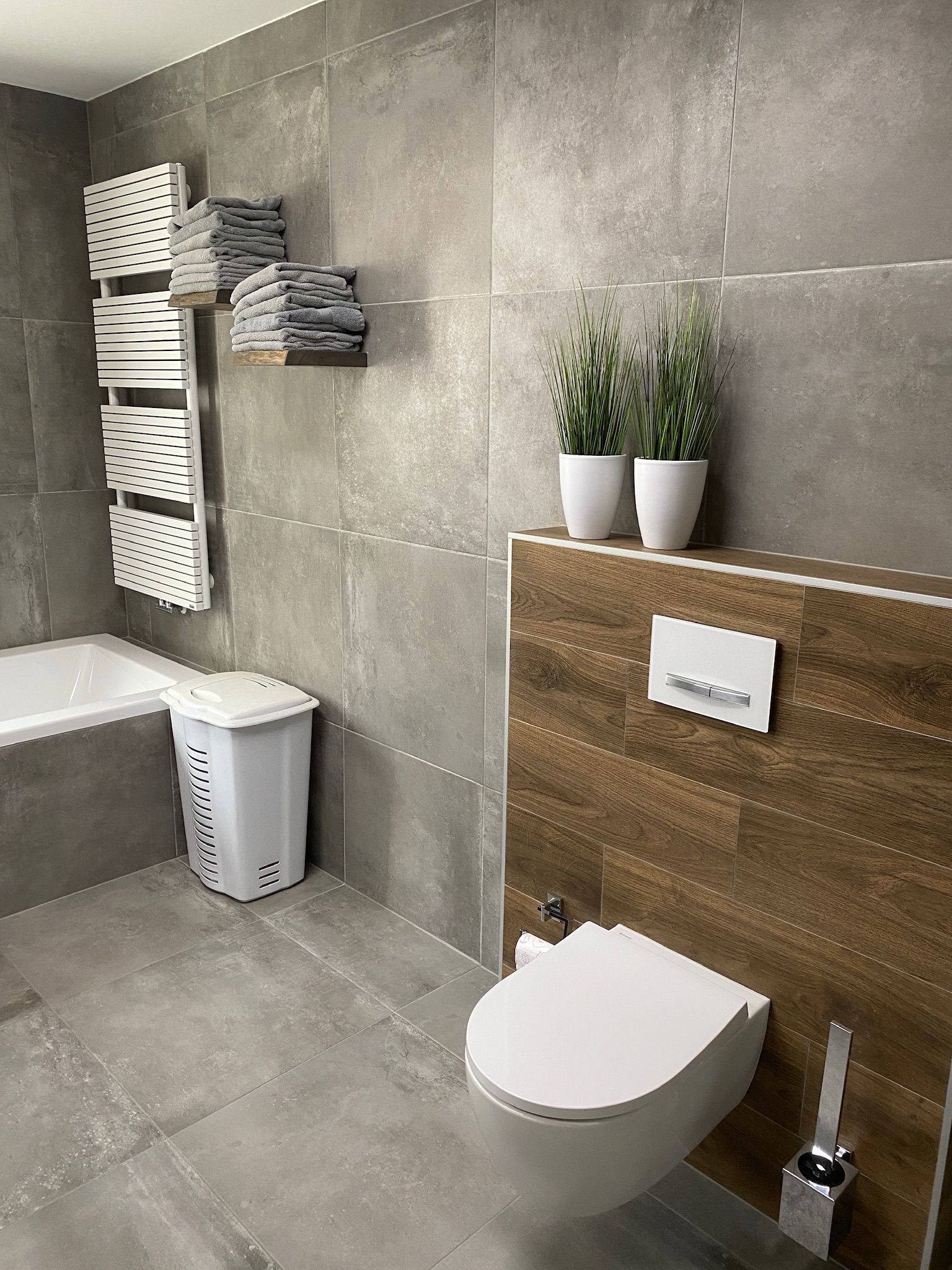 Toiletwand met houtlooktegels, hangtoilet en witte handdoekradiator