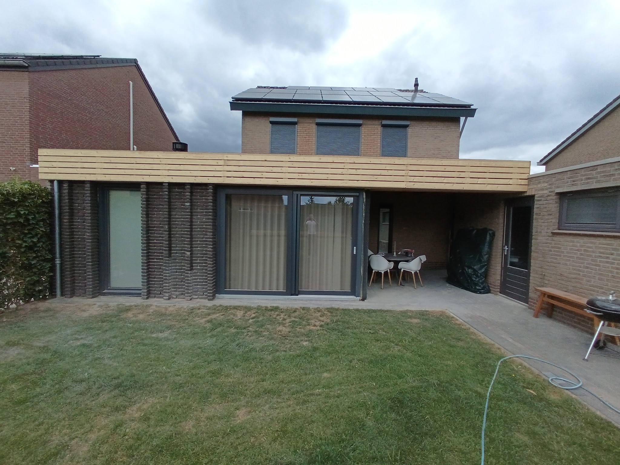 Afgewerkte aanbouw met schuifpui, plat dak en terras